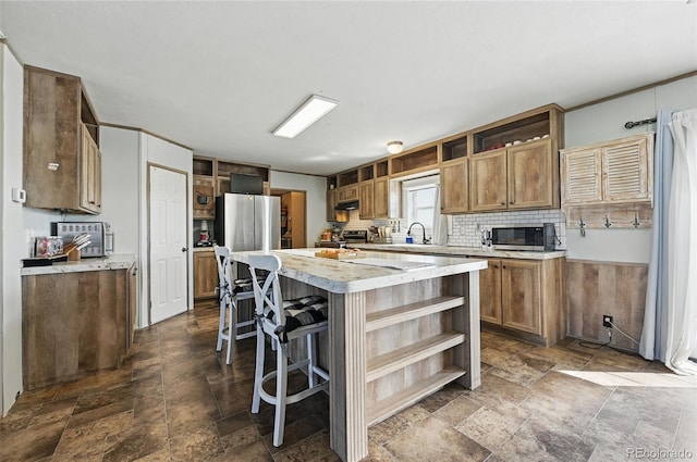 30890 Ken Vw, Yoder, CO 80864 - kitchen featuring open shelves, appliances with stainless steel finishes, dark stone finish floors, a center island, and light countertops
