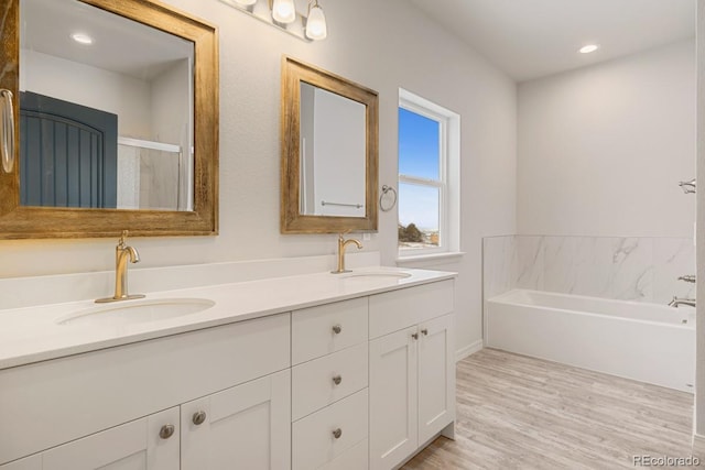 bathroom featuring hardwood / wood-style flooring, vanity, and a tub to relax in