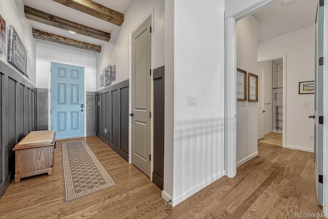 hall with beam ceiling and light wood-type flooring