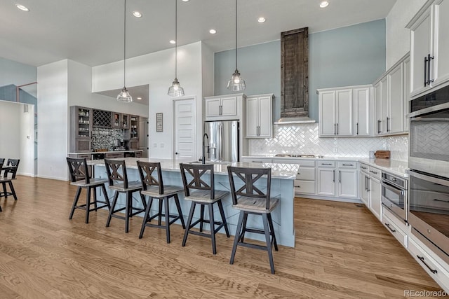 kitchen featuring white cabinets, a breakfast bar, a towering ceiling, and a spacious island