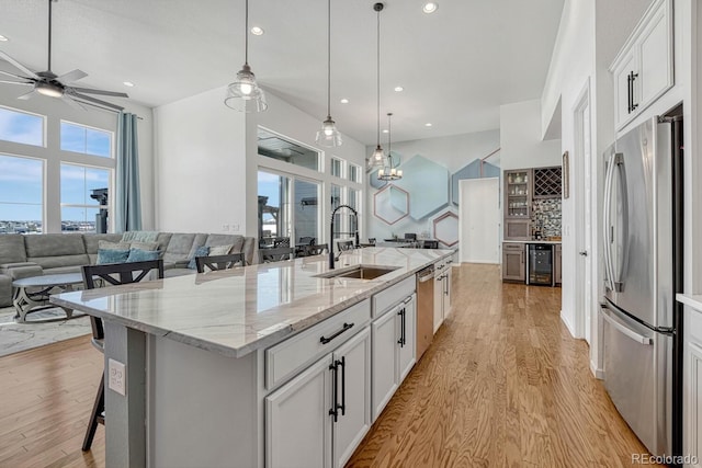 kitchen with stainless steel fridge, sink, white cabinetry, wine cooler, and a breakfast bar area