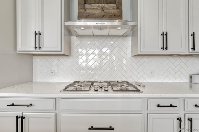 kitchen with backsplash, light stone counters, wall chimney range hood, white cabinets, and stainless steel gas stovetop