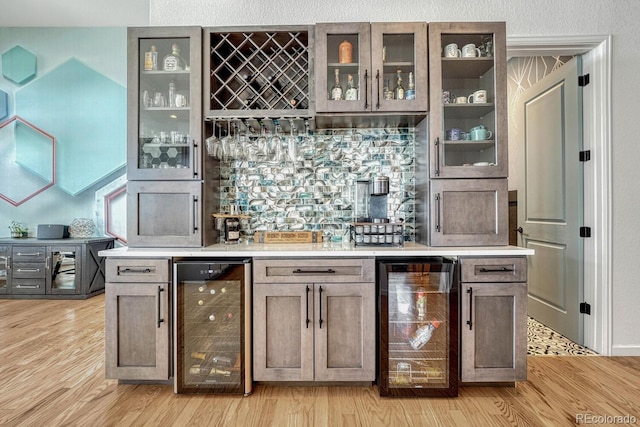 bar with light hardwood / wood-style floors and beverage cooler