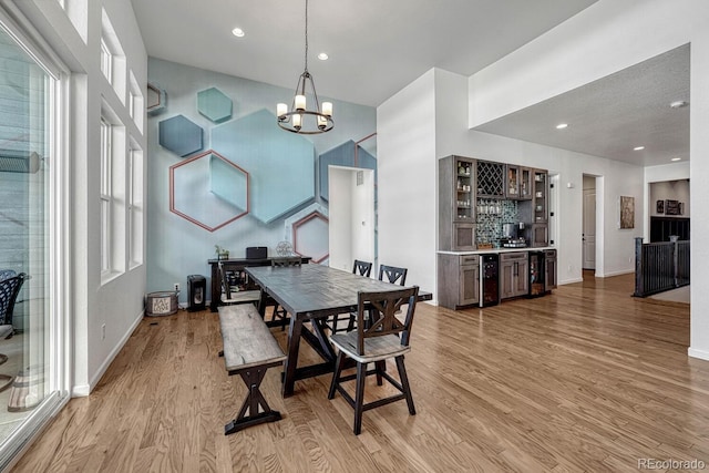 dining space featuring plenty of natural light, light hardwood / wood-style flooring, indoor bar, and an inviting chandelier