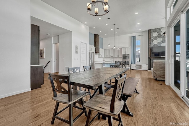 dining space with a chandelier, sink, light hardwood / wood-style floors, and a high ceiling