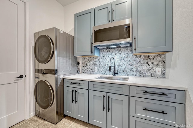 laundry area featuring cabinets, sink, light tile patterned floors, and stacked washer and dryer