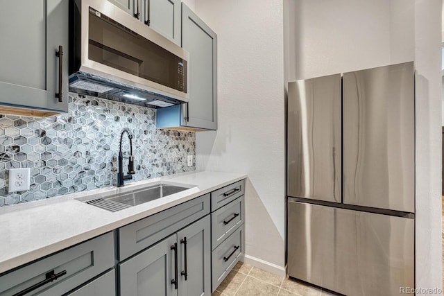 kitchen featuring gray cabinetry, decorative backsplash, sink, and stainless steel appliances