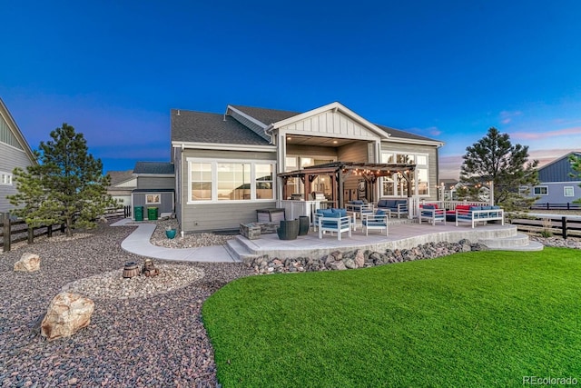 back house at dusk with a pergola, a patio area, and a yard