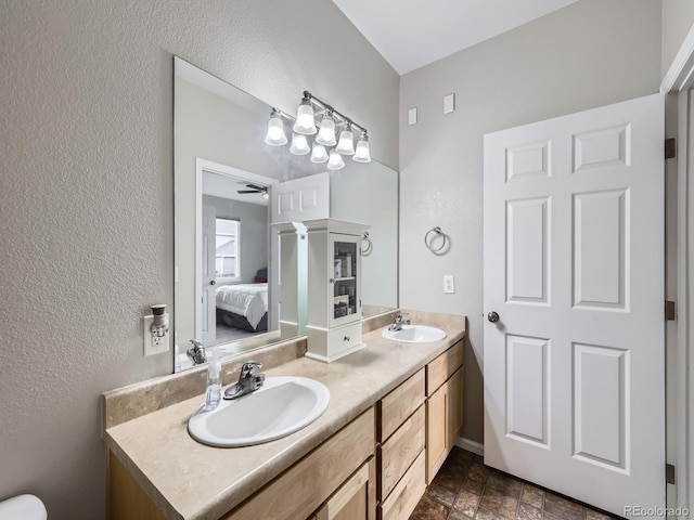 8481 W Union Ave Unit 4-203, Littleton, CO 80123 - ensuite bathroom featuring double vanity, ceiling fan, a textured wall, and stone finish flooring