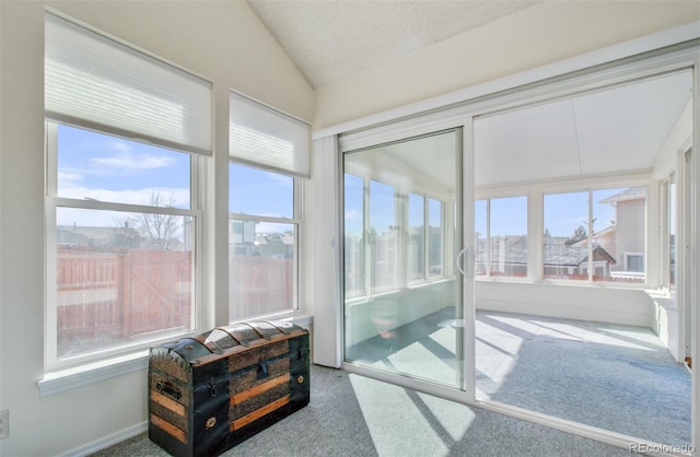 sunroom featuring carpet flooring, a textured ceiling, and lofted ceiling