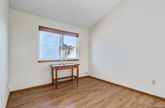 unfurnished room with light wood-style flooring, baseboards, and lofted ceiling