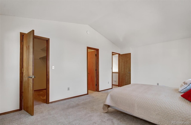 carpeted bedroom with a closet, a spacious closet, and lofted ceiling