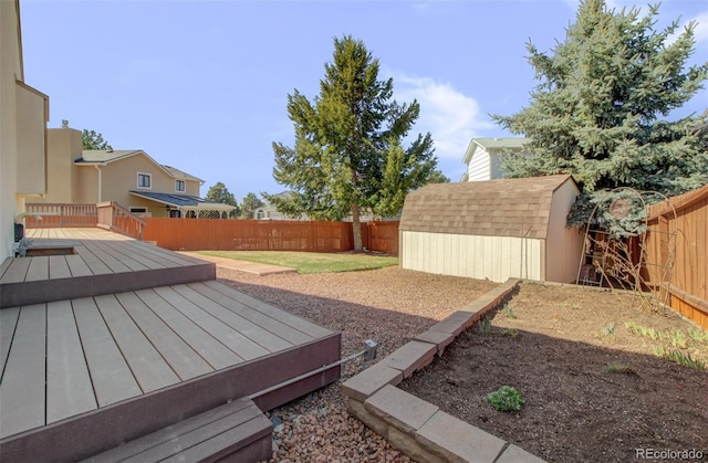 view of yard with an outbuilding, a fenced backyard, a wooden deck, and a storage unit