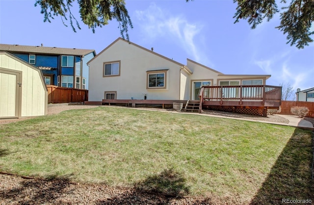 back of property featuring an outbuilding, a fenced backyard, a lawn, a storage unit, and a deck