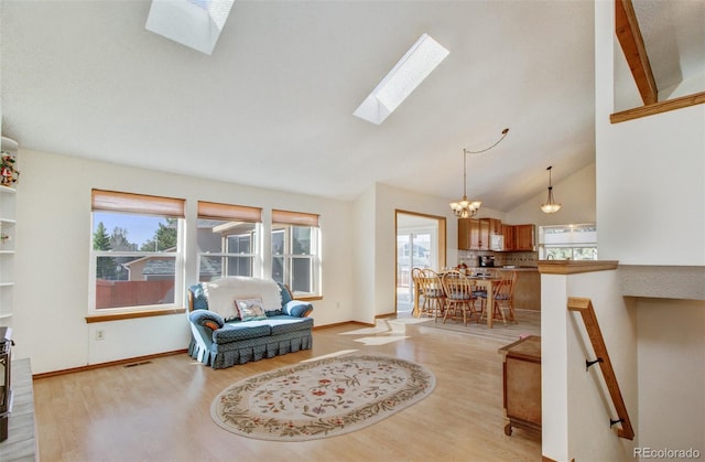 sitting room with a chandelier, high vaulted ceiling, light wood-style flooring, and a skylight