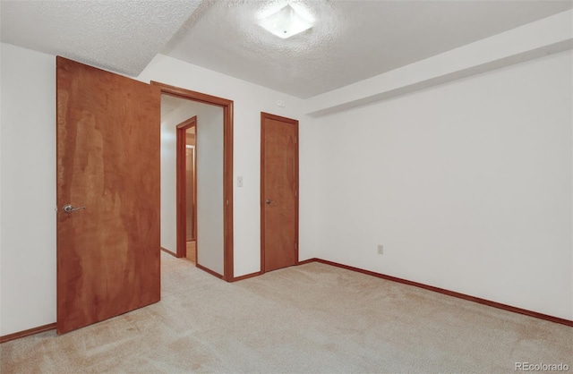 unfurnished bedroom with light carpet, a closet, baseboards, and a textured ceiling