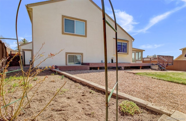 back of house with a deck, stucco siding, and fence