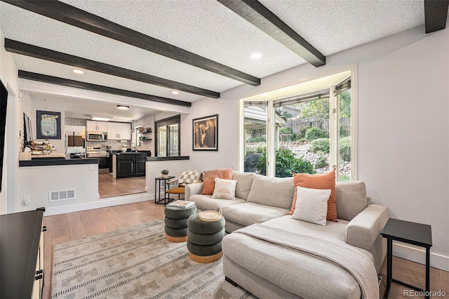 6251 W 74th Ave, Arvada, CO 80003 - living room featuring beamed ceiling, a textured ceiling, light wood-style floors, baseboards, and recessed lighting
