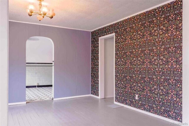 tiled spare room with a notable chandelier and ornamental molding