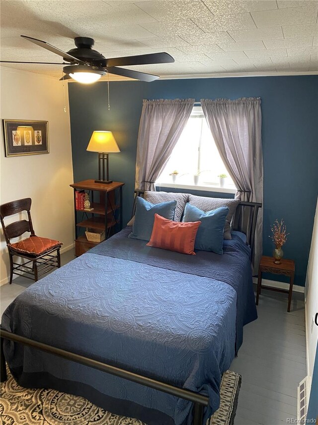 bedroom featuring ceiling fan, a textured ceiling, and wood-type flooring