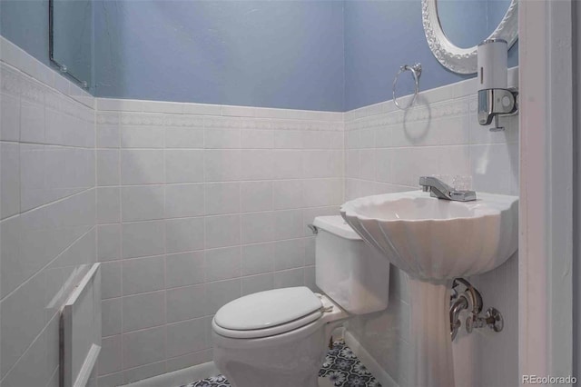 bathroom with tile patterned floors, tile walls, and toilet