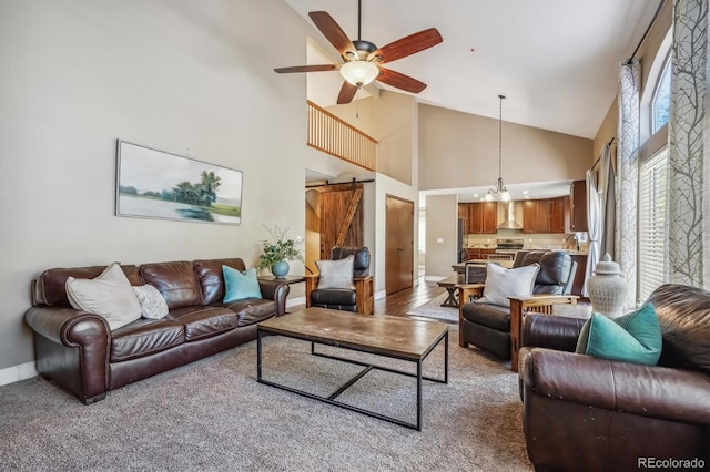 living room featuring a barn door, hardwood / wood-style floors, ceiling fan with notable chandelier, sink, and high vaulted ceiling