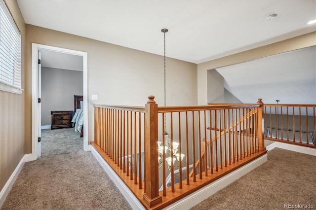 hall with an inviting chandelier and carpet flooring