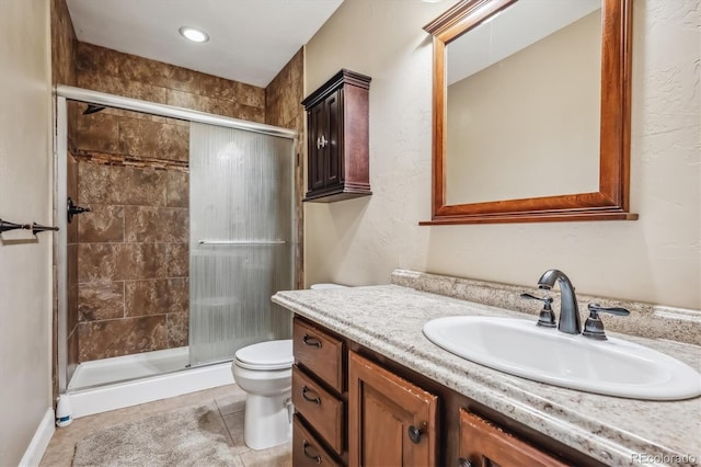 bathroom with tile patterned flooring, walk in shower, toilet, and vanity