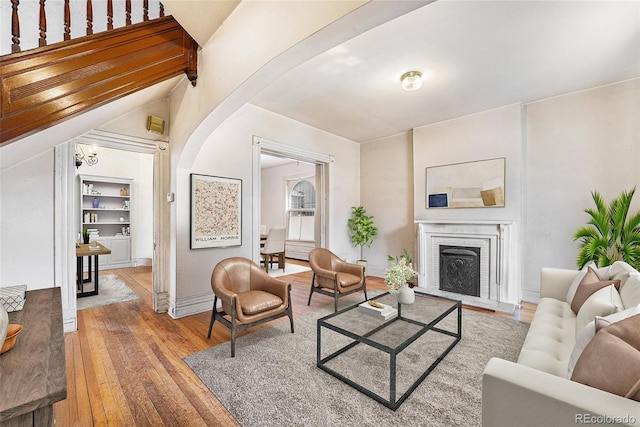 2350 N Ogden St, Denver, CO 80205 - living area with hardwood / wood-style floors, arched walkways, a brick fireplace, built in shelves, and baseboards