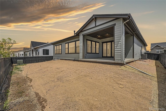 back house at dusk featuring a patio area and central AC