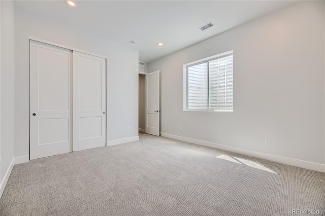 unfurnished bedroom featuring light colored carpet and a closet