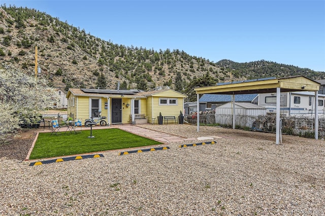 back of house featuring solar panels, a mountain view, a carport, and an outbuilding