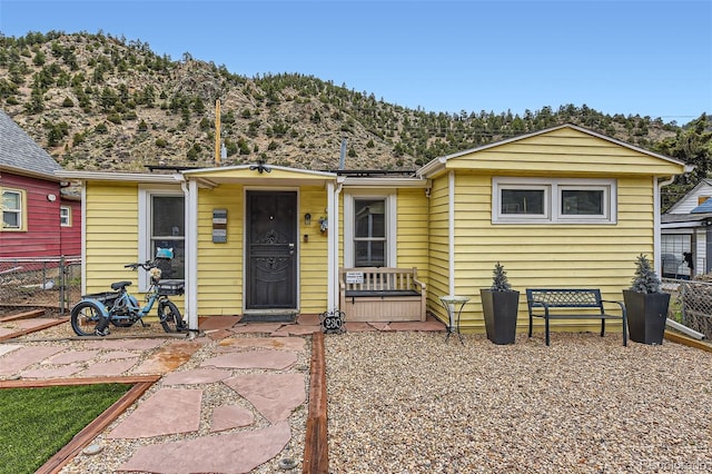 view of front of house with a mountain view and fence