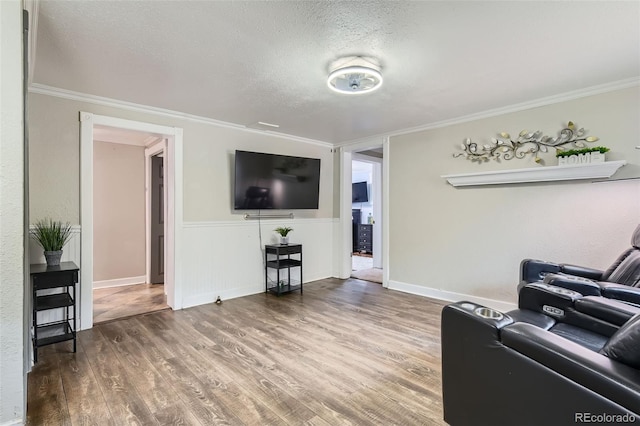 living room with a textured ceiling, wood finished floors, crown molding, and baseboards
