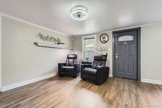 sitting room with a textured ceiling, wood finished floors, crown molding, and baseboards