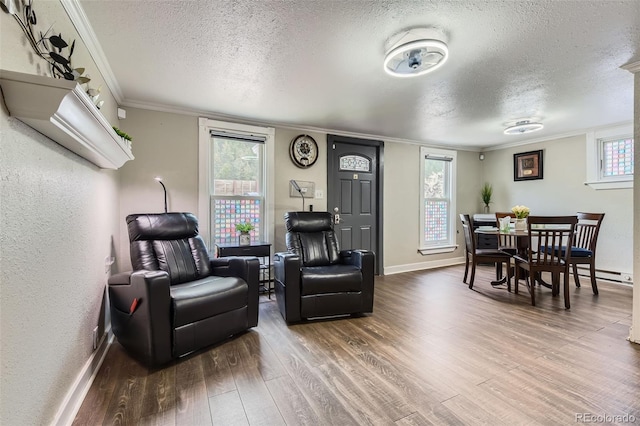 living area featuring a textured ceiling, wood finished floors, ornamental molding, and baseboards