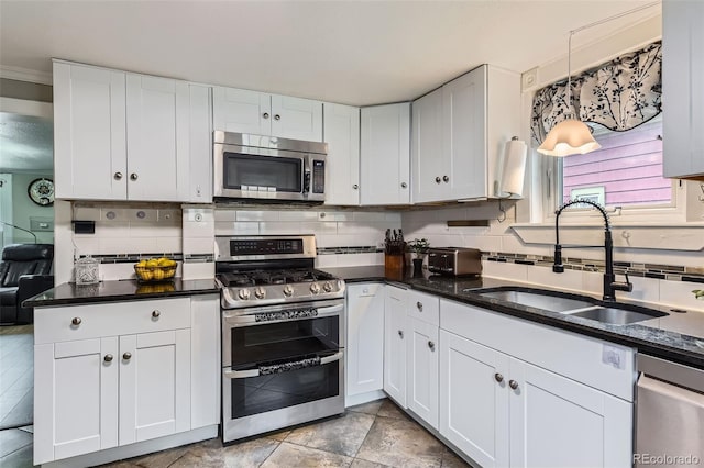 kitchen with stainless steel appliances, a sink, decorative backsplash, and white cabinetry