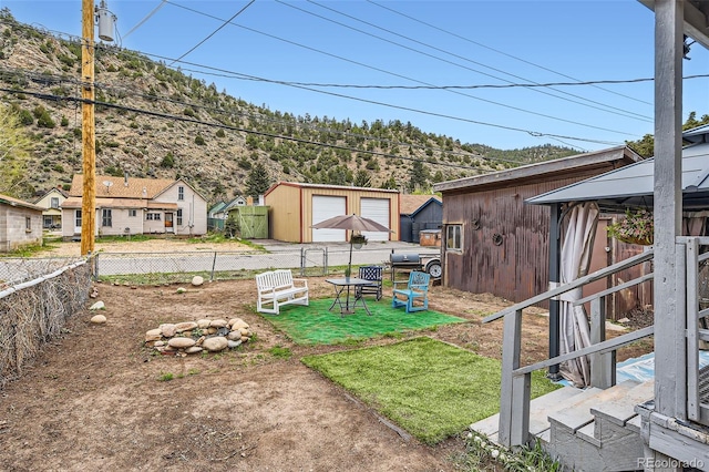 view of yard featuring fence, a garage, a mountain view, and a gazebo