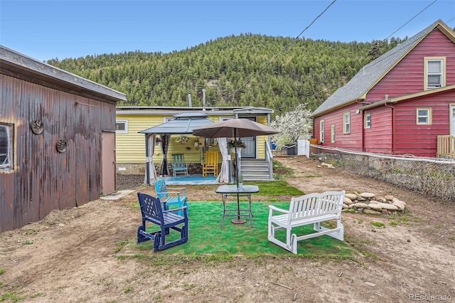 view of yard featuring a forest view, a gazebo, and fence
