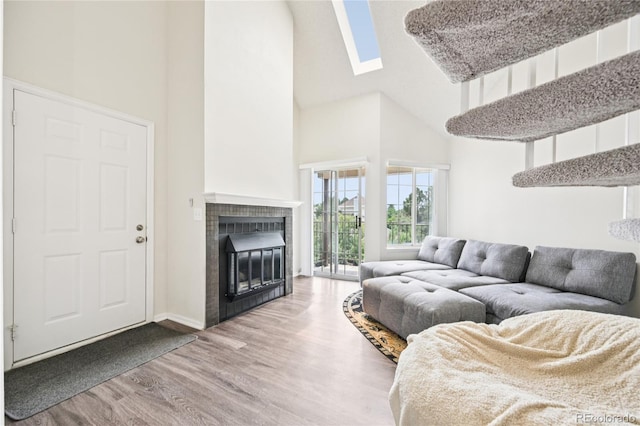 13873 E Lehigh Ave Unit C, Aurora, CO 80014 - living room featuring a towering ceiling, wood finished floors, a fireplace, and a skylight