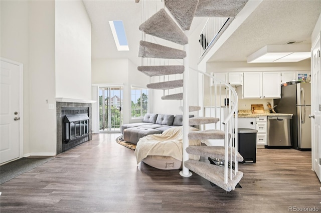 13873 E Lehigh Ave Unit C, Aurora, CO 80014 - living room featuring a towering ceiling, stairs, wood finished floors, a skylight, and a fireplace