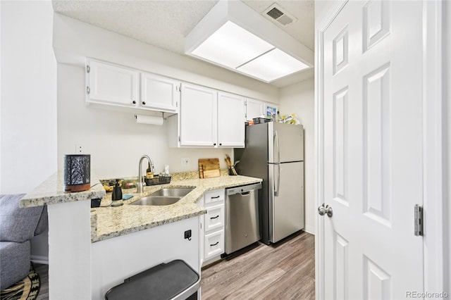 13873 E Lehigh Ave Unit C, Aurora, CO 80014 - kitchen featuring appliances with stainless steel finishes, light wood-style floors, white cabinetry, and light stone countertops