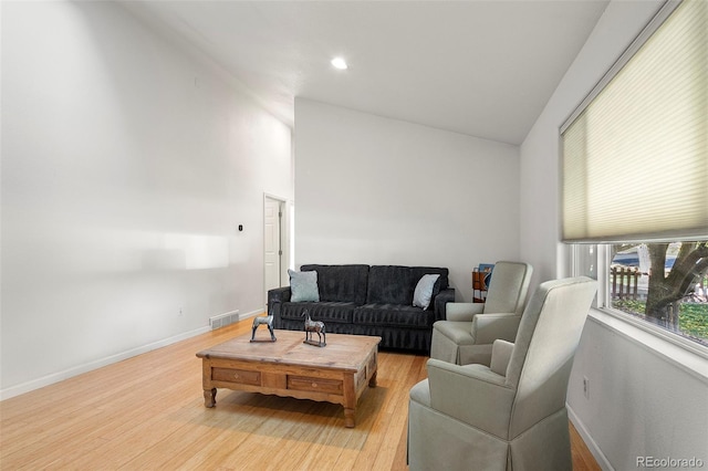 living room with baseboards, lofted ceiling, light wood finished floors, and visible vents