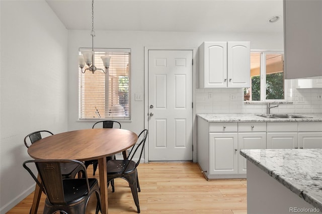 kitchen with white cabinetry, tasteful backsplash, sink, and pendant lighting