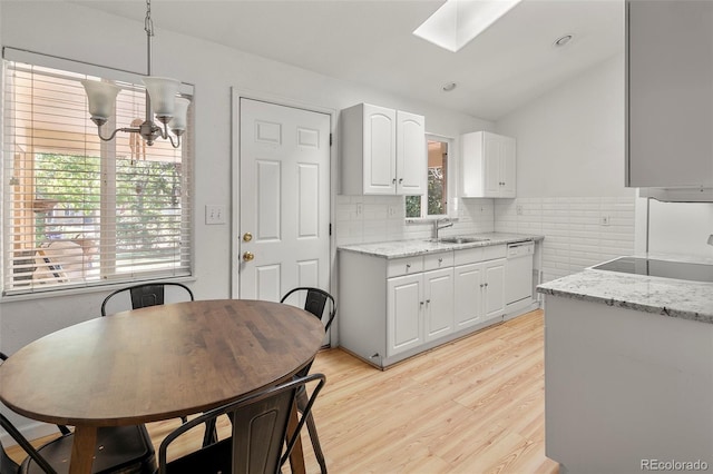 kitchen featuring white cabinetry, light stone counters, a sink, light wood-style flooring, and dishwasher