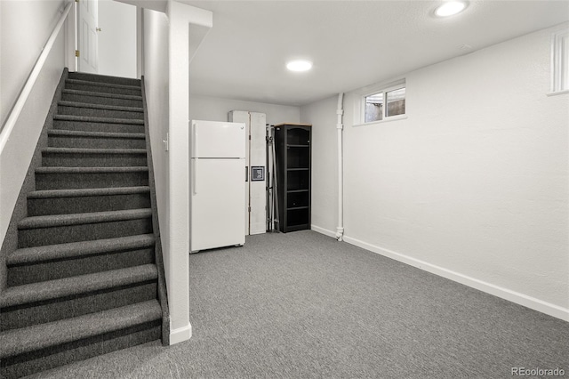 below grade area with freestanding refrigerator, stairs, baseboards, recessed lighting, and carpet flooring