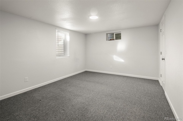 unfurnished room with baseboards, dark colored carpet, and a textured ceiling