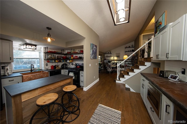 kitchen featuring black gas range, hanging light fixtures, white cabinetry, and dark wood-type flooring