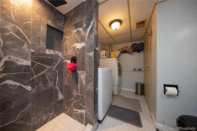 bathroom with a tile shower, a paneled ceiling, and washer and dryer