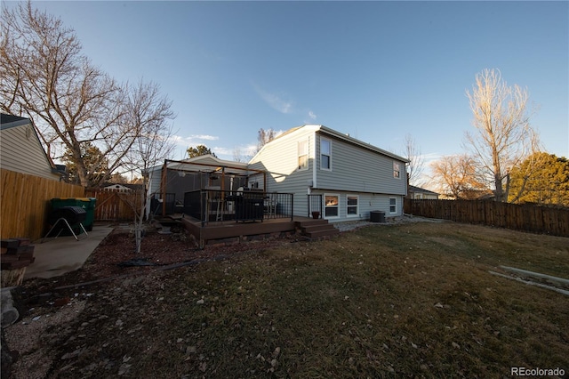 rear view of house with cooling unit, a wooden deck, and a lawn